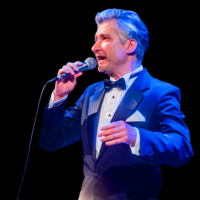 Photo of the singer - a man in a suit and bow tie singing to a microphone