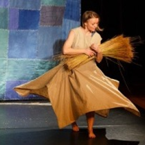 Photo from the performance: a woman with a bundle of flax.