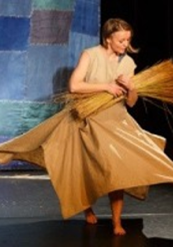Photo from the performance: a woman with a bundle of flax.