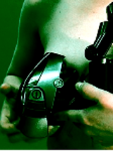 Photo of a naked woman who is holding a black metal object. Green background.