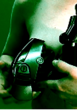 Photo of a naked woman who is holding a black metal object. Green background.