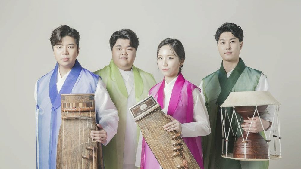 Photo of the band - three men and one woman stnding in their folk clothes with their musical instruments.