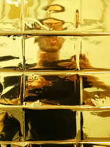 Photo of a person standing behind yellow, glass wall.