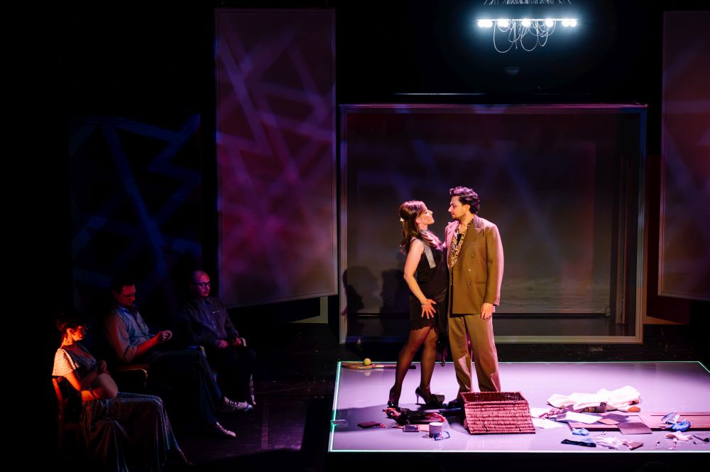 Aktorka ze sztucznym ciążowym brzuchem i aktor w okularach siedzą na krzesłach.