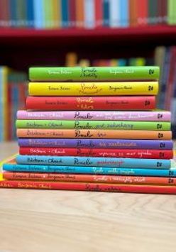 Stos kolorowych książek ułożonych na blacie.