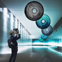 Stojący w pomieszczeniu człowiek przygląda się podwieszonym do sufitu kręgom różnego koloru.