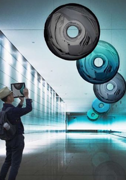 Stojący w pomieszczeniu człowiek przygląda się podwieszonym do sufitu kręgom różnego koloru.