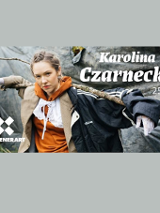 Na banerze widzimy Karolinę czarnecką ubraną w wiele warstw ubrań różnego koloru, trzymającą na ramionach gałąź. W prawym górnym rogu biały napis Karolina Czarnecka i data 25. lipca. W lewym dolnym rógu białe logo i napis KontenerArt.