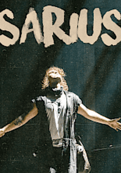 Na zdjęciu widać artystę z rozłożonymi rękoma i zadartą do góry głową.