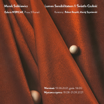 Dwie brązowe kulki na bordowym nieregularnie ułożonym materiale.