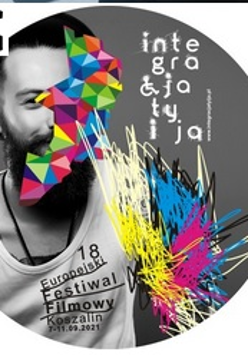 Grafika przedstawia czarnobiałą fotografię brodatego mężczyzny w białym podkoszulku z pełną nazwą festiwalu. Lewe ramię mężczyzny zamazane jest kolorowymi kreskami: żółtymi, niebieskimi, czerwonymi i białymi. Połowa twarzy mężczyzny zasłonięta jest przez geometryczny kształt. Kształt składa się z różnokolorowych trójkątów.