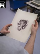 Na zdjęciu widać dłonie uczestnika pracowni, trzymające czarno-białą grafikę.