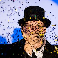 Fotografia mężczyzny w cylindrze a przed nim padające konfetti.