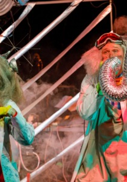 Na zdjęciu widać dwoje naukowców, kobietę i mężczyznę o siwych, bujnych włosach. Bohaterka Nielemka ubrana jest w czerwony kombinezon oraz biały fartuch opatrzony różnymi wzorami chemicznymi i matematycznymi. Bohater Lemtak ma widoczne na czole okulary i dmucha w rurę wentylacyjną, z której wylatuje dym.