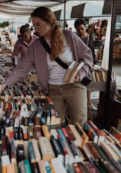 Kobieta przebierająca w książkach wystawionych na bazarze.