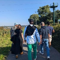 Grupa ludzi spacerująca wśród zieleni.