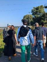 Grupa ludzi spacerująca wśród zieleni.