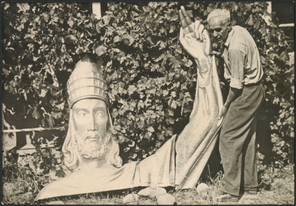 Czarno-białe zdjęcie architekta przy rzeźbie Chrystusa.