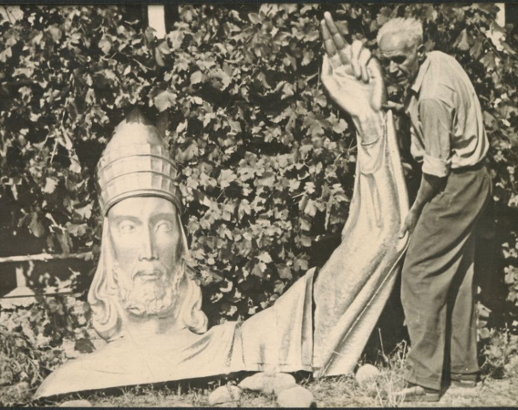 Czarno-białe zdjęcie architekta przy rzeźbie Chrystusa.