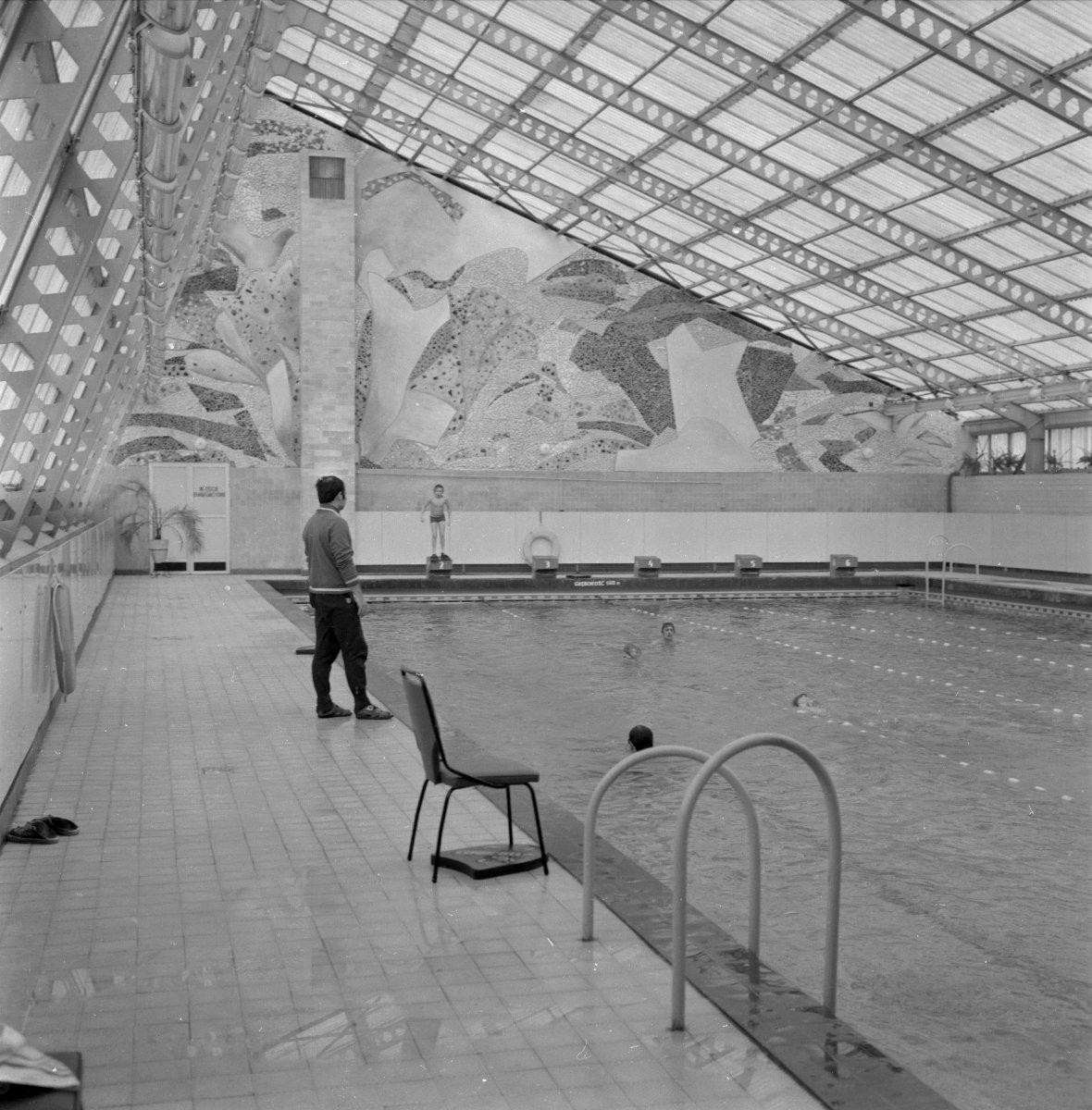 Czarno-białe zdjęcie basenu z korzystającymi z niego ludźmi.