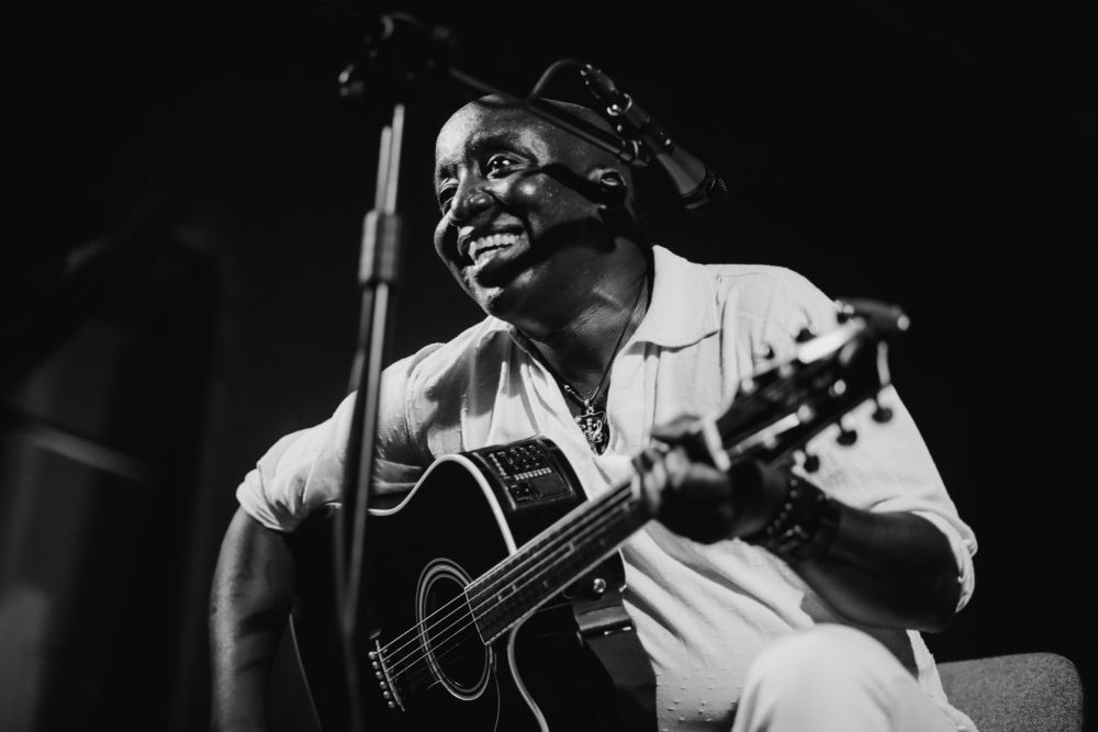 Czarno-białe zdjęcie czarnoskórego muzyka bluesowego z gitarą.