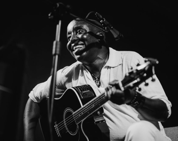 Czarno-białe zdjęcie czarnoskórego muzyka bluesowego z gitarą.