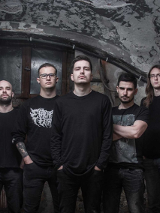 Zdjęcie pięciu mężczyzn w czarnych koszulkach, którzy stoją na tle odrapanej ściany.