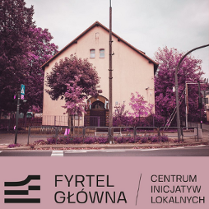 Budynek ze skośnym dachem i stojące przy nim fioletowe drzewa.