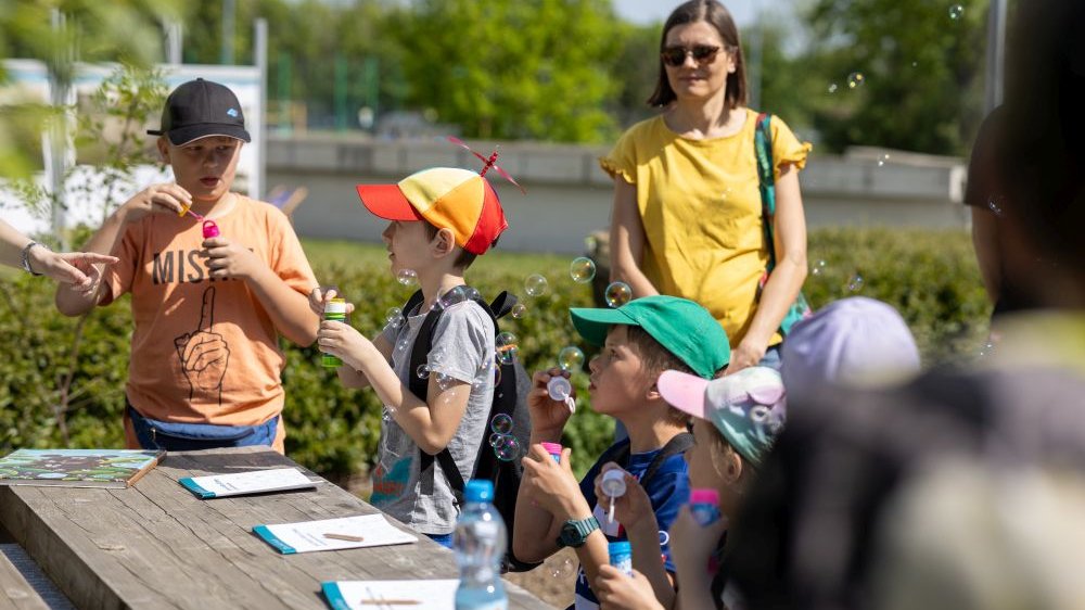Dorośli i dzieci puszczają bańki mydlane.
