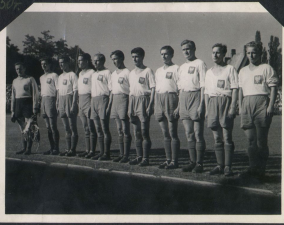 Drużyna piłkarska na boisku, zawodnicy stoją w rzędzie.