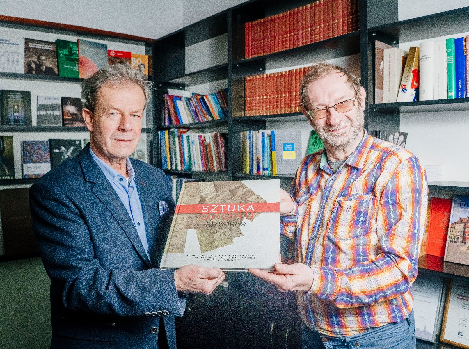Dwaj mężczyźni trzymają w rękach książkę-album