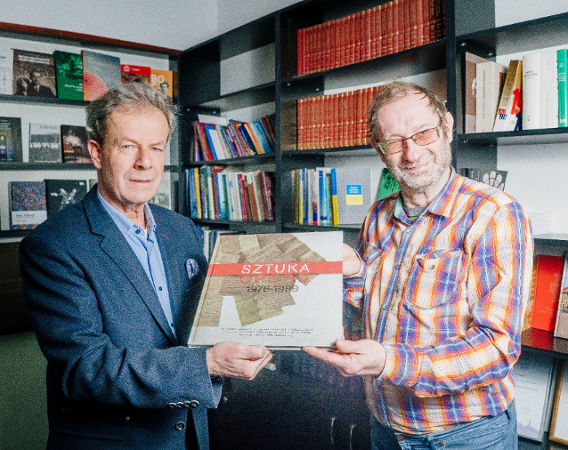 Dwaj mężczyźni trzymają w rękach książkę-album