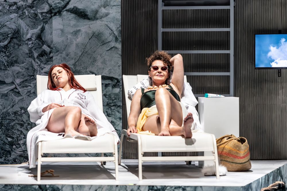 Dwie kobiety leżą na leżakach plażowych.