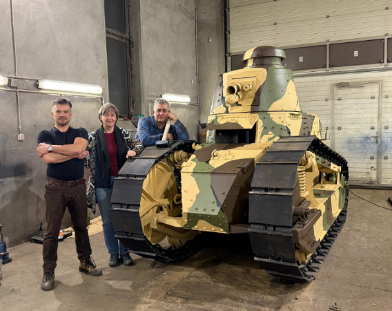 Dwóch mężczyzn i kobieta przy czołgu starego typu, malowanie pancerza w plamy, szerokie gąsienice