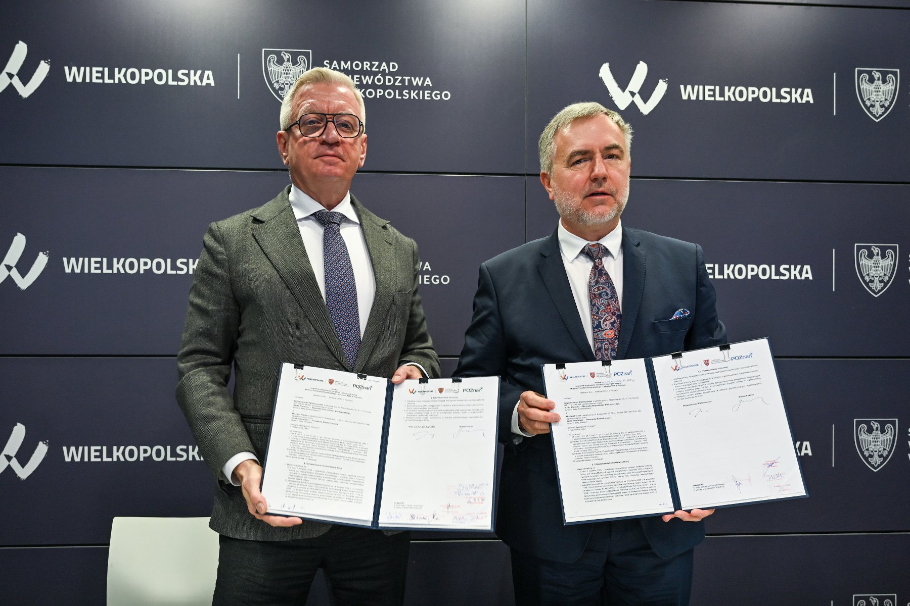 Dwóch mężczyzn prezentuje dokumenty z umową