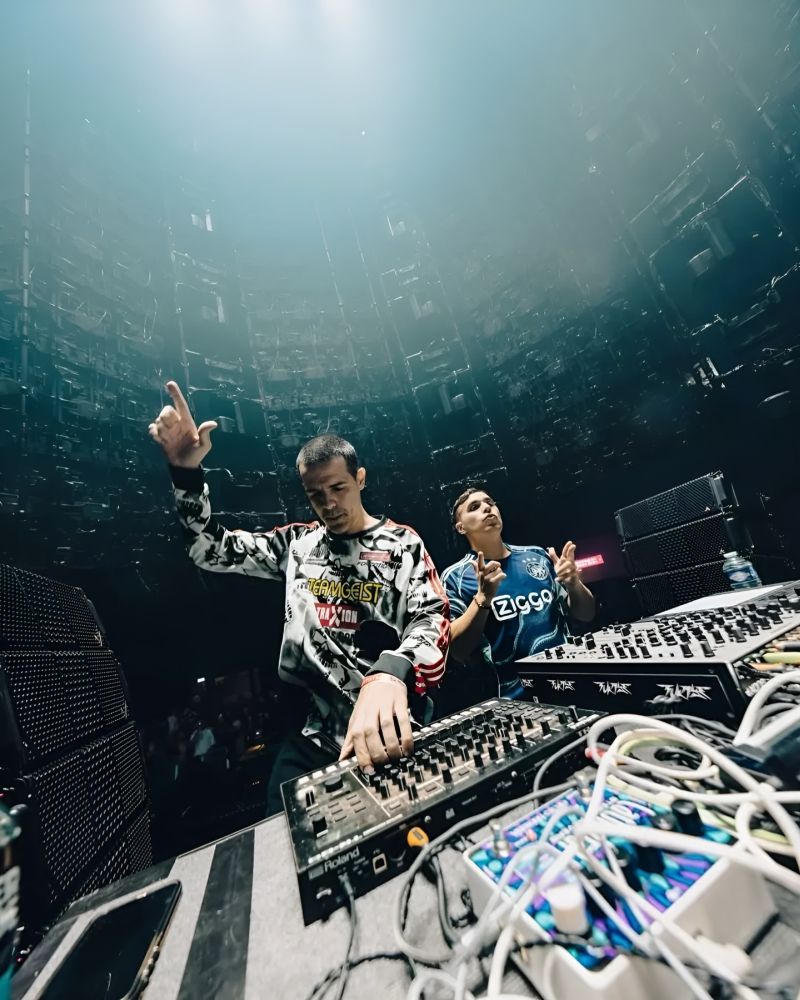 Dwóch mężczyzn za konsoletami didżejskimi.