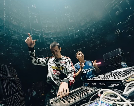 Dwóch mężczyzn za konsoletami didżejskimi.