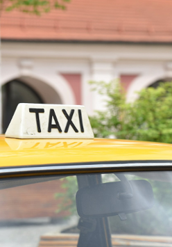 Zdjęcie, dach żółtego samochodu, na nim napis Taxi.