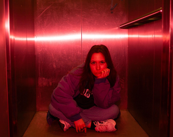 Dziewczyna siedzi na podłodze w windzie lub w szafie