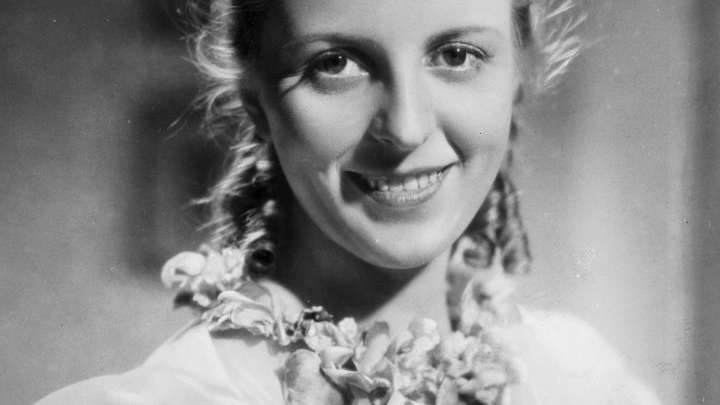 Czarno-biały kadr filmowy z podpisem aktorki. To jej uśmiechnięty portret.