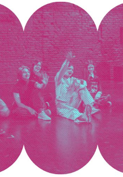 Grupa młodzieży siedzi na podłodze w sali gimnastycznej z prowadzącym zajęcia. Kadr na różowym tle.