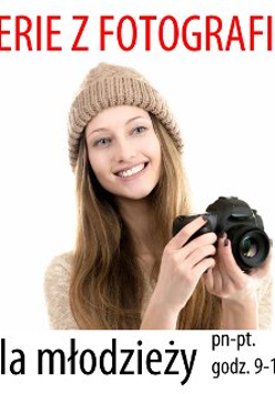 Zdjęcie przedstawia uśmiechniętą panią w czapce, trzymającą w dłoniach aparat.