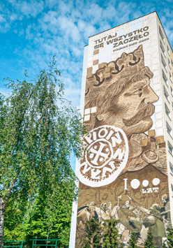Ogromy mural na bocznej ścianie bloku mieszkalnego, z twarzą Bolesława Chrobrego, rysunkami średniowiecznych wojów i podpisem o treści tutaj się wszystko zaczęło.