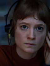 Kadr z filmu, młoda dziewczyna z słuchawkami na uszach wpatruje się przed siebie.