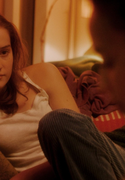 Kobieta siedzi na kanapie, opierając głowę na ręce.