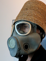 Mężczyzna w masce gazowej i wiklinowym koszu na głowie.