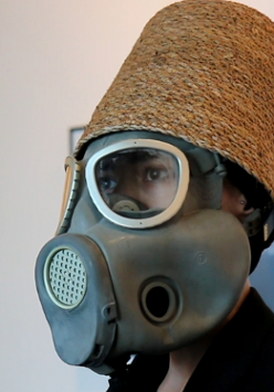 Mężczyzna w masce gazowej i wiklinowym koszu na głowie.