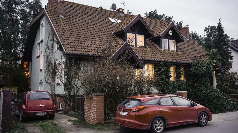 Zdjęcie przedstawia Dom z Bajki. Przed domem stoi czerwony samochód. Dom otaczają także drzewa.