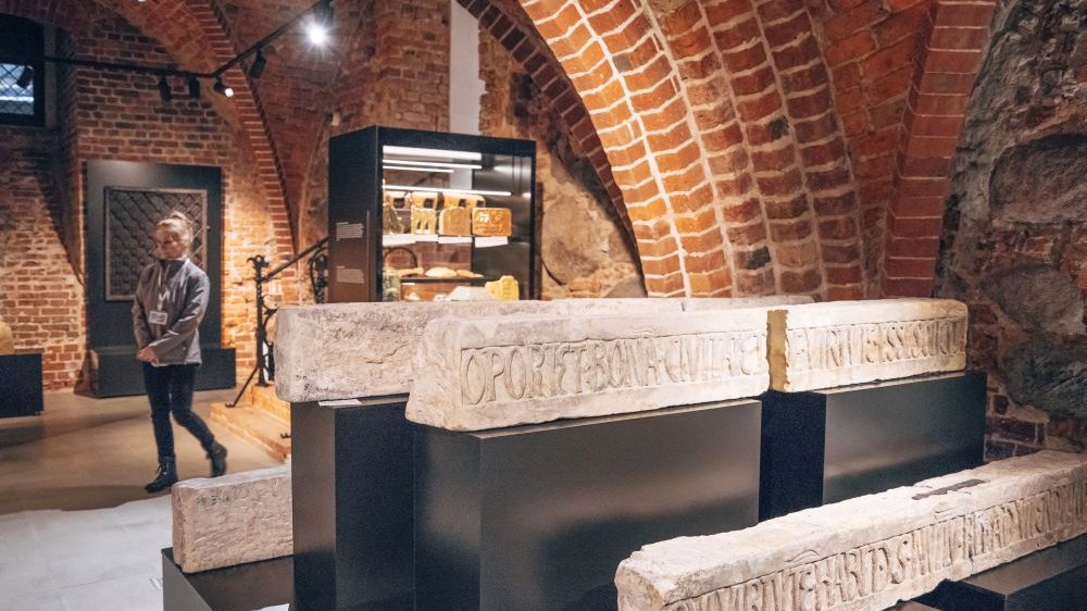 Wykonane z kamienia fragmenty architektury z łacińskimi napisami na ekspozycji.