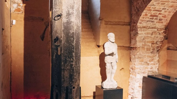 Pręgierz poznański i stojąca obok figurka kata (pierwotnie przymocowana do jego szczytu) w ratuszowej sali z cegły.